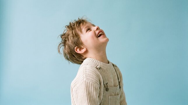 Adorable young boy's face lights up with infectious laughter, gazing heavenward, embodying pure joy and innocent childhood wonder