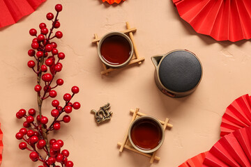 Obraz premium Teapot with cups of tea, berries and Chinese symbols on beige background. New Year celebration