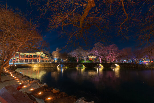 Serene twilight view of the illuminated Gwanghallu Pavilion overlooking a calm pond surrounded by bare winter trees and glowing ground lanterns in Namwon.