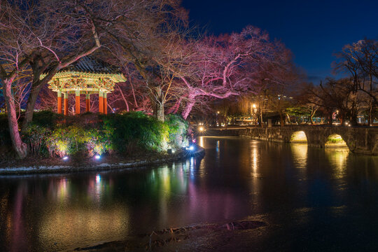 Serene twilight view of the illuminated Gwanghallu Pavilion overlooking a calm pond surrounded by bare winter trees and glowing ground lanterns in Namwon.