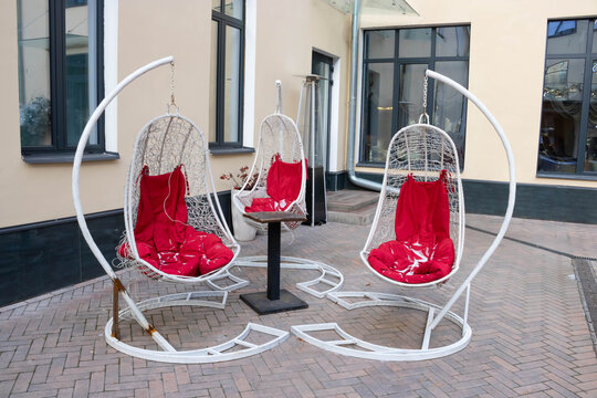 Three white capsule-shaped hanging rocking chairs are located in the outdoor patio