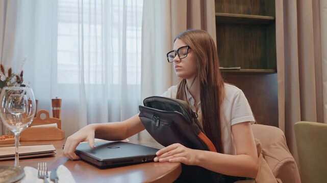 White woman writer hugging laptop at window table, quiet solitude with glass and curtains, reflective pause before leaving, protective embrace of device, soft evening light and introspective creative