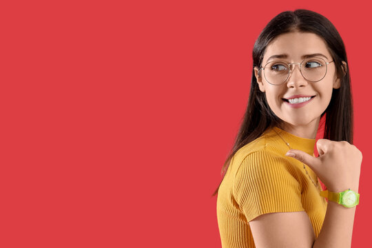 Young gossip woman pointing at something on red background
