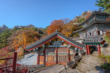 Obraz premium Beautiful autumn landscape of the historic Dobongsan Mangwolsa Temple surrounded by colorful fall foliage and rocky peaks in Bukhansan National Park.