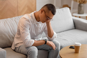 Fototapeta premium Young man looking at wristwatch in room
