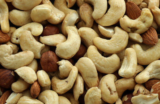 Almond and cashew nuts in big pile on table close up. Large amount of brown nuts