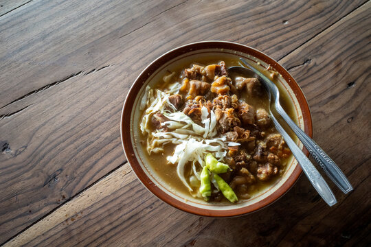 Tongseng Kambing, a spicy curry made from goat meat, on an old wooden table
