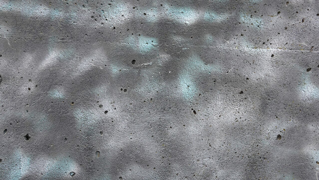 Close-up of rough concrete wall texture with grey and light blue spray paint
