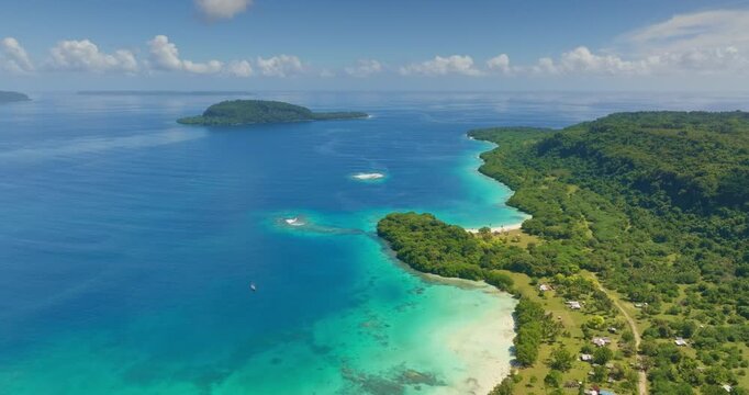 Tegua coastline, lush tropical forest, white sand beach and clear turquoise water, small shoreline village and distant islands dotting vast Pacific horizon, serene paradise on Torres Islands, Vanuatu