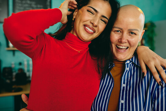 Happy diverse friends embracing diverse women showing support and strength with a cancer survivor smile
