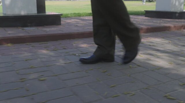 Lower body close up view showing military officer legs wearing olive green trousers with red piping and polished black leather shoes 