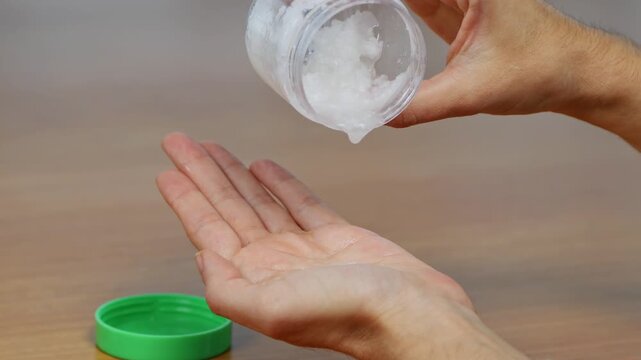 Young female caring for dry hands with moisturizing petroleum jelly during a relaxing beauty and skincare session.