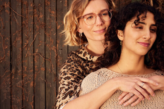 Two diverse friends embrace in a warm setting, showcasing diversity and friendship