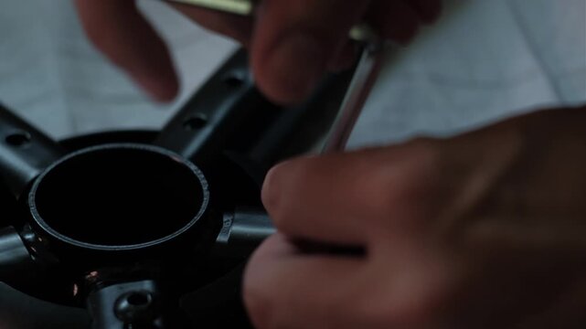 Close-up static shot of using allen wrench to tighten gaming chair base during indoor furniture assembly and DIY setup
