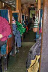 Fototapeta premium Interior view of an old railway carriage with blue upholstered seats, wooden partitions, passengers, and a narrow aisle, showing nostalgic heritage rail travel and classic public transport.