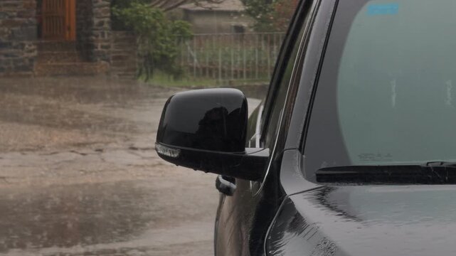 Dark Vehicle Side Mirror and Windshield in Heavy Rain