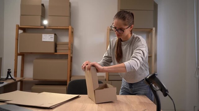 Woman packing boxes in home workspace, business logistics and packaging services. e-commerce and business concept.