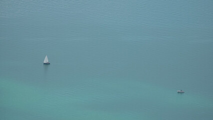 Naklejka premium Aerial minimalist view of a sailboat and a motorboat on the turquoise waters of Lake Geneva, Switzerland