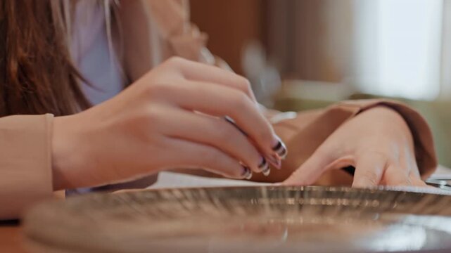 Closeup of writing hands on wooden table. Focused scene of someone jotting personal notes carefully. Intimate moment captured of individual reflecting through handwritten notes at cozy desk
