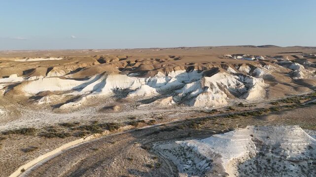 Drone view of a dry, waterless stream bed in the hilly semi-desert of Mangystau. Low chalk hills and parched earth highlight the region's arid climate. A unique geological landscape in Kazakhstan demo