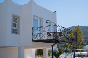 Obraz premium Balcony with chairs overlooking the sea on a sunny day near a white building in a coastal town