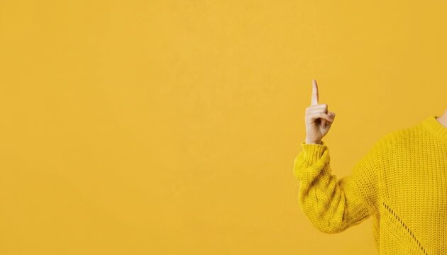 A person wearing a yellow sweater pointing upwards against a bright yellow background
