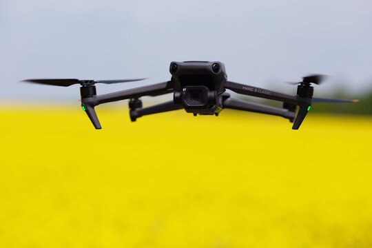 Drohne DJI Mavic 3 Classic fliegt an einem Rapsfeld.