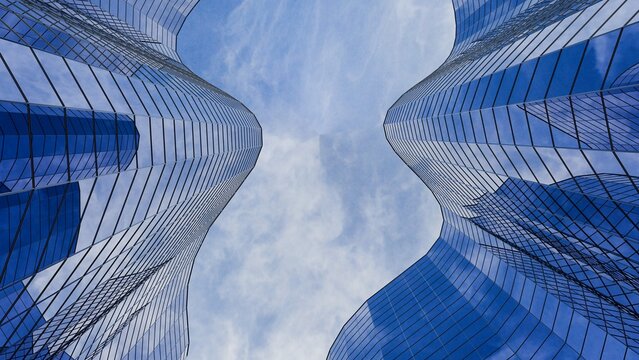 Low angle view of 3D modern blue glass skyscrapers with curved facades under a cloudy blue sky