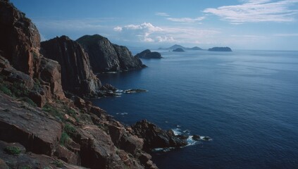 Obraz premium Dramatic Coastal Cliffs Overlooking a Serene Blue Ocean Under a Cloudy Sky.