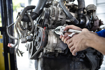 Fototapeta premium Mechanic checks undercarriage with focused care. Technician smiles while holding diagnostic tool. Partner observes attentively, leaning slightly forward. Workshop tools and equipment surround them