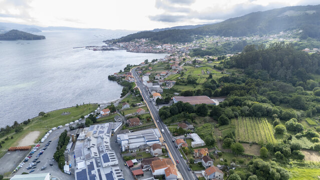Aerial view of the coastal village featuring residential houses and a winding road along the bay surrounded by lush green hills Casalvito, Pontevedra, Spain.