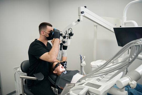 Focused male dentist examining apprehensive female child patient