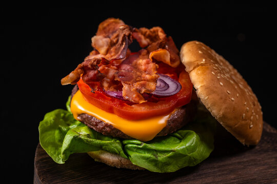 Foto orizzontale di un Hamburgher con bacon, formaggio, pomodoro, cipolla e insalata