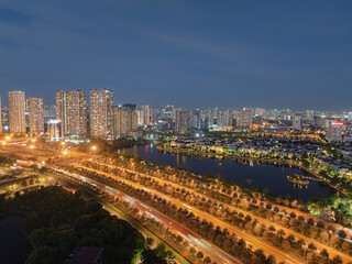 Night aerial photograph of Hanoi boulevard with glowing traffic trails, lakeside apartments, and illuminated urban skyline. © Hanoi Photography