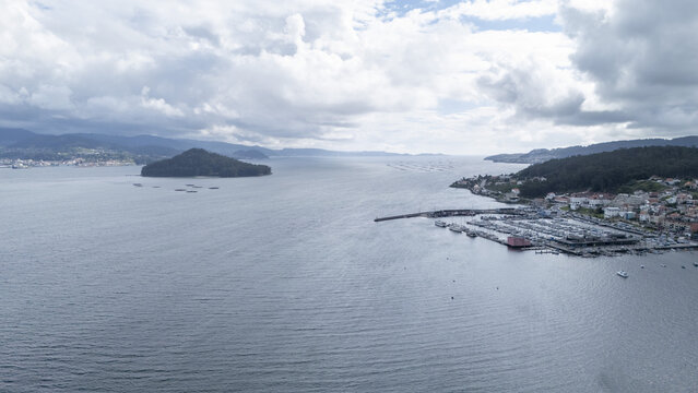 Aerial view of the historic coastal town and marina overlooking the Ria de Pontevedra with Tambo Island under a cloudy sky in Combarro, Pontevedra, Spain.