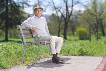 Obraz premium Smiling senior man sitting on a park bench