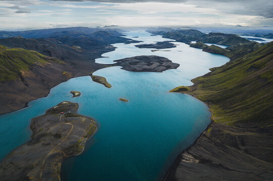 Aerial view of Langisjor lake with its turquoise waters winding through dark volcanic mountains and green mossy slopes under a cloudy sky Skaftarhreppur, Iceland.