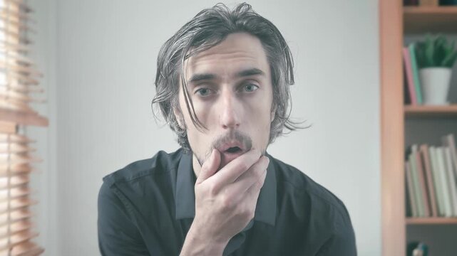 Surprised and Deep in Thought, a Man in a Softly Lit Room Shows Evolving Expressions of Bewilderment and Realization, with Hand Gestures Enhancing the Contemplative Atmosphere