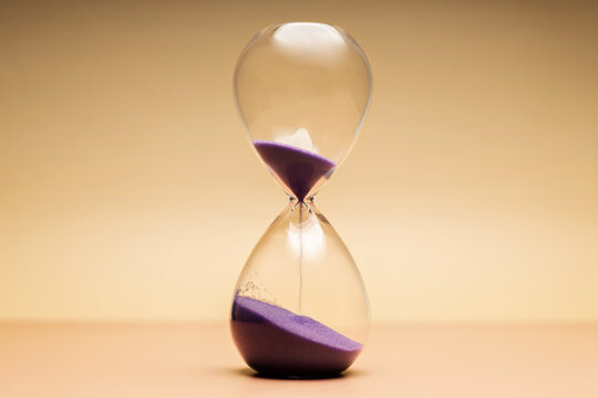 Hourglass with purple sand, passing time, aging process and life transition concepts