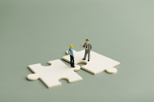 Miniature businessmen on connected jigsaw puzzle ,business partnership, teamwork