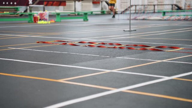 Empty badminton court with net and clear court lines on glossy indoor floor distant benches and green equipment, minimal spectators, quiet prepractice atmosphere, wideangle composition showing