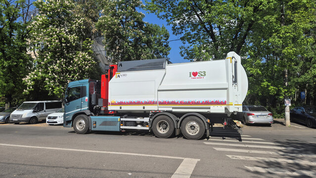 A large, modern blue and white garbage truck driving on a city street with "I Love S3" branding. Picture taken on May 11, 2026 in Bucharest, Romania.