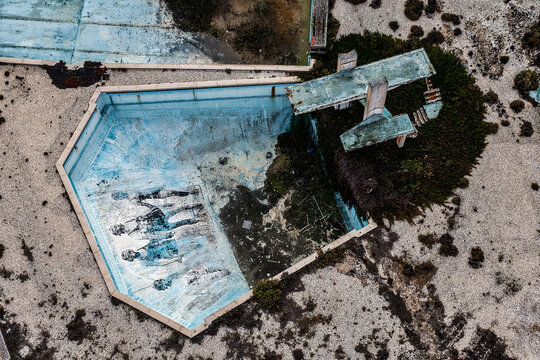 Aerial view of the abandoned swimming pool at Praia de Sao Pedro de Moel featuring a diving board and weathered murals in Marinha Grande, Leiria, Portugal.