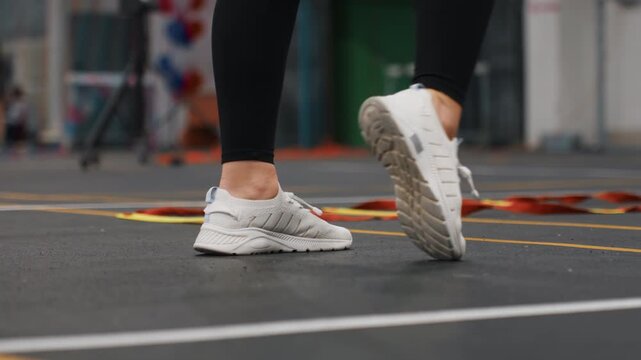 Badminton court footwork showing white sneakers and black leggings executing precise steps during solo training drill on indoor court focused rhythm balance and agility improvement