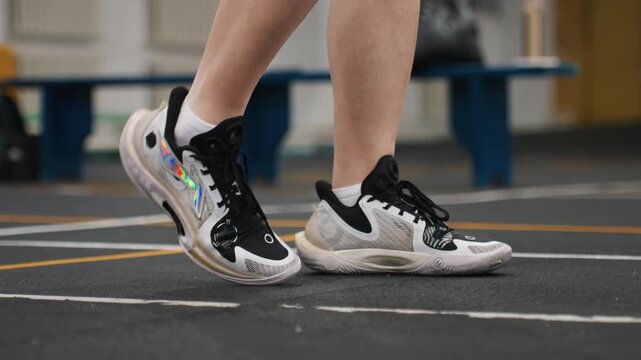 Badminton technical footwork drill court finesse player demonstrating controlled heeltotoe steps, sneaker detail, calm tempo, lowangle profile, bench background, emphasis on balance and precision