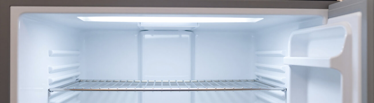 wide shot open empty freezer drawer bathed bright cold fluorescent lighting revealing clean stainless steel shelves awaiting