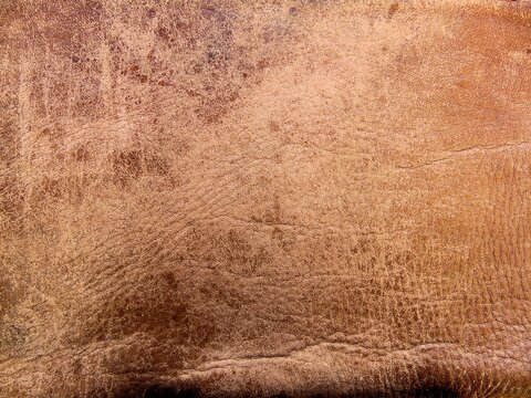 Vintage weathered brown leather texture background. Old shabby leather surface with cracks and scuffs, rustic material close-up.