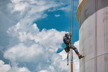 Male worker rope access industrial working at height tank oil wearing harness, helmet safety equipment rope access inspection of thickness © chitsanupong