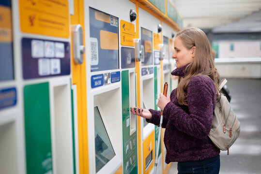 Visually impaired woman standing on the train station and buying ticket
