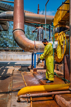 Male workers dressing in protective shower detoxification suit clean up after sealing a leaking container
